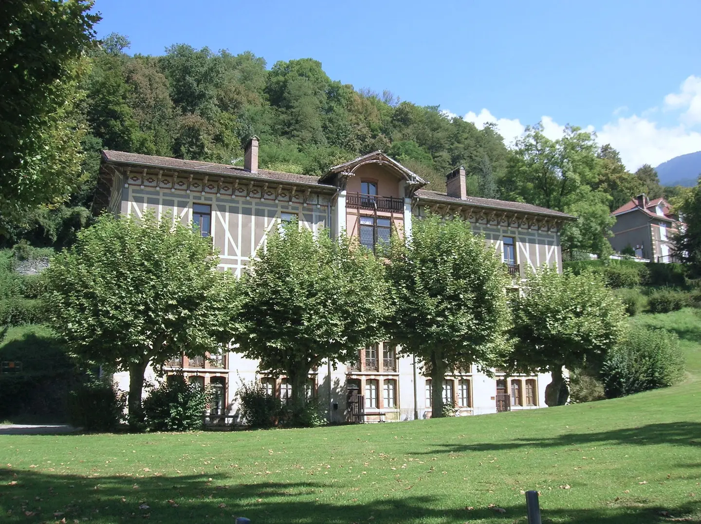 A Belle Époque villa on the edge of the Uriage spa park, with pruned lime trees and a sunny lawn